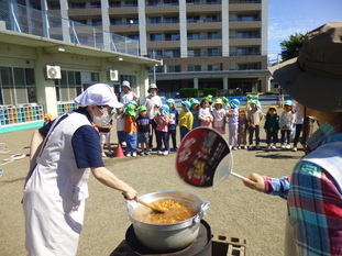 園庭でカレー作りをしている写真。