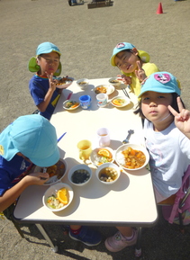 園庭で手作りカレーを食べる写真