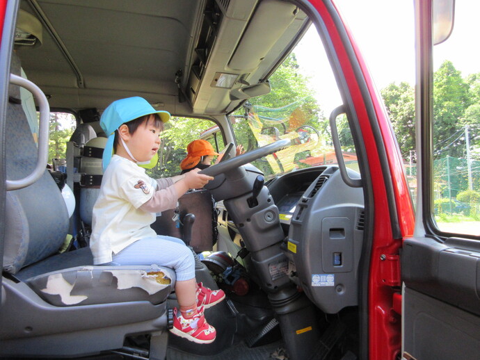 男の子が消防車に乗っている写真