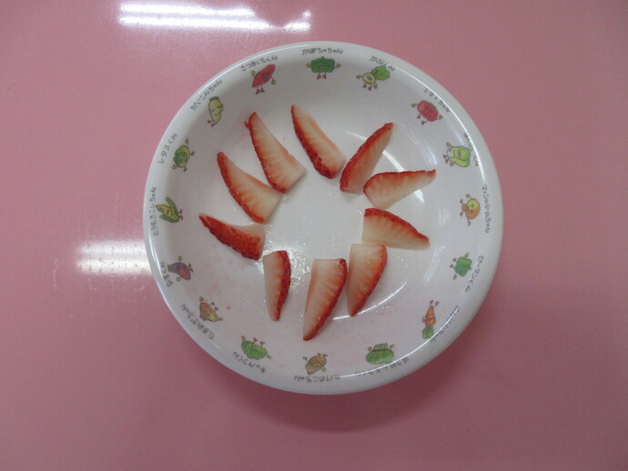 イチゴを切って皿に並べている写真