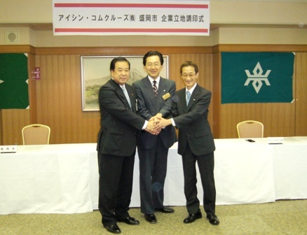 握手をする谷藤市長、達増岩手県知事、上田アイシン・コムクルーズ社長の写真