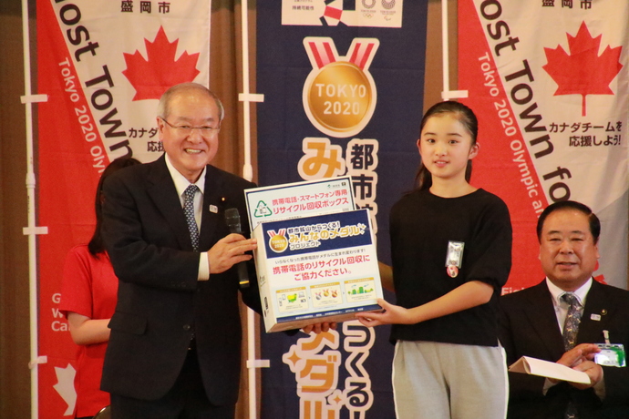 回収ボックスを鈴木オリンピック・パラリンピック担当大臣から受け取る鈴木結稀さん