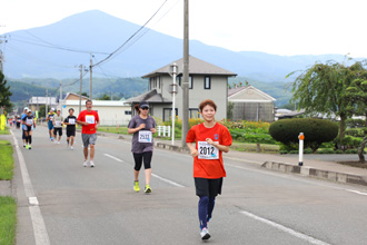 姫神山をバックに走るランナーの写真