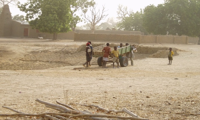 写真：荷車を押す村の子どもたちの左にあるのがモスクです。
