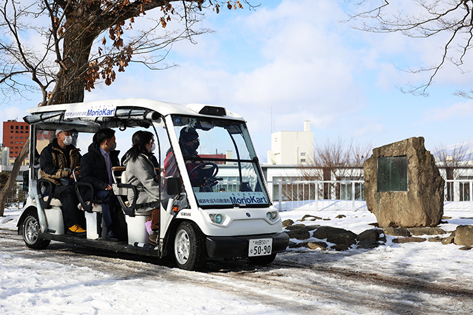 石川啄木の歌碑前でガイドの説明を聞く搭乗者