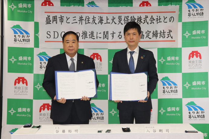 連携協定締結式の写真。協定書を手にする谷藤市長（左）と同社の入谷剛司岩手支店長